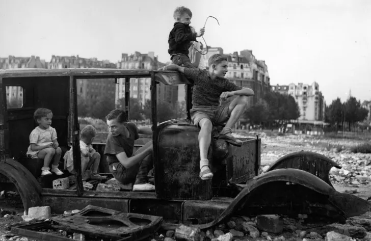 Photo de Doisneau représentant des enfants s'amusant sur une carcasse de voiture